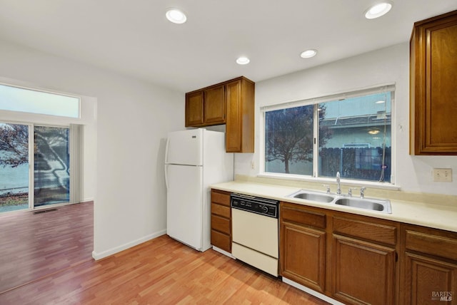 kitchen with a healthy amount of sunlight, sink, light hardwood / wood-style floors, and white appliances