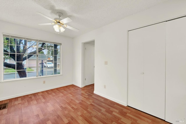 unfurnished bedroom with ceiling fan, a textured ceiling, and light wood-type flooring