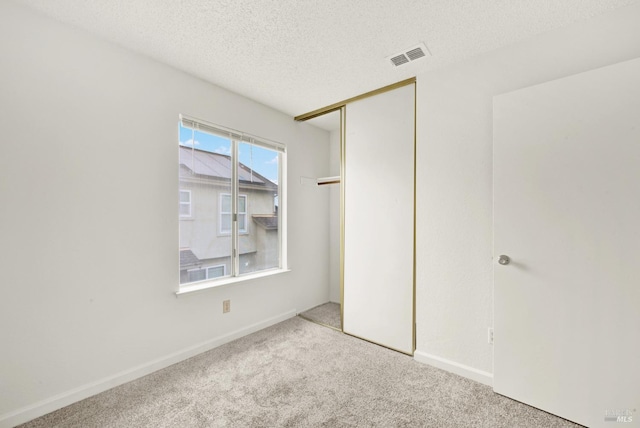 unfurnished bedroom with light carpet, a closet, and a textured ceiling