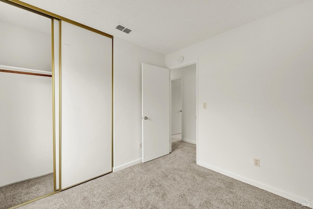 unfurnished bedroom with a closet and light colored carpet