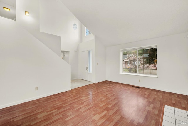 unfurnished living room featuring light hardwood / wood-style floors and a high ceiling