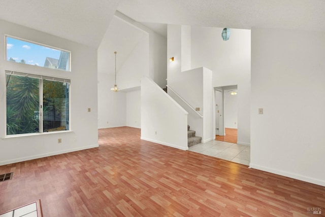 unfurnished living room featuring high vaulted ceiling and light hardwood / wood-style flooring