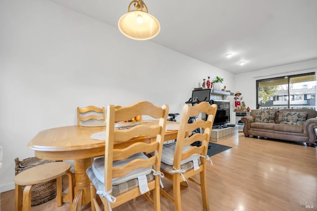 dining area with a tiled fireplace and light hardwood / wood-style flooring