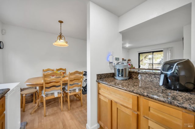 kitchen with decorative light fixtures, light hardwood / wood-style floors, and dark stone countertops