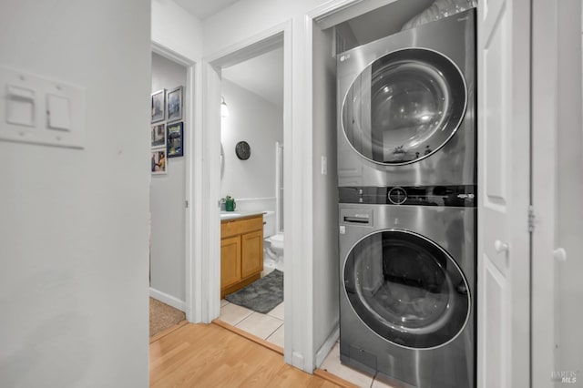 clothes washing area featuring stacked washing maching and dryer and light hardwood / wood-style flooring