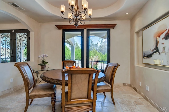 dining space with an inviting chandelier and a raised ceiling