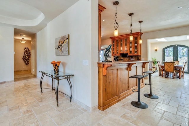 bar with hanging light fixtures, decorative backsplash, and french doors