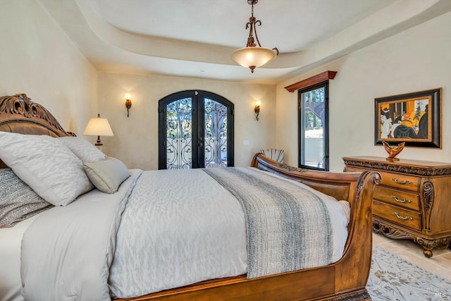 bedroom featuring access to exterior, a tray ceiling, french doors, and light tile patterned floors