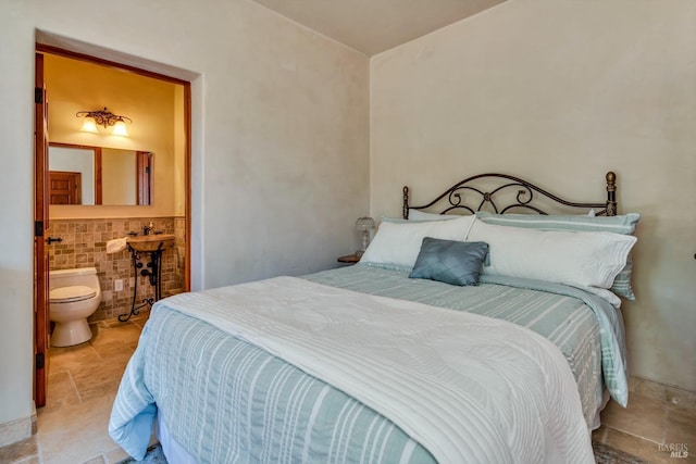 bedroom with connected bathroom and tile walls