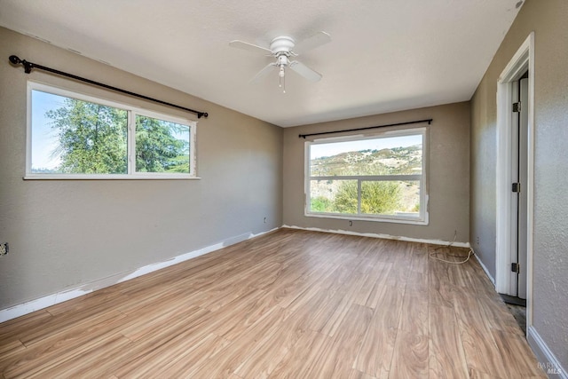 empty room with a wealth of natural light, baseboards, and light wood finished floors