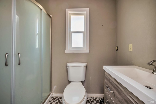 bathroom with a stall shower, baseboards, vanity, and toilet