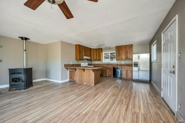 kitchen featuring black dishwasher, light countertops, brown cabinetry, stainless steel fridge, and a kitchen bar