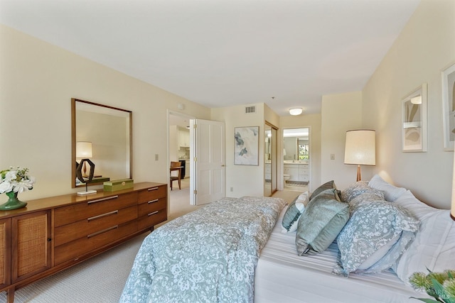 bedroom with light colored carpet and ensuite bathroom