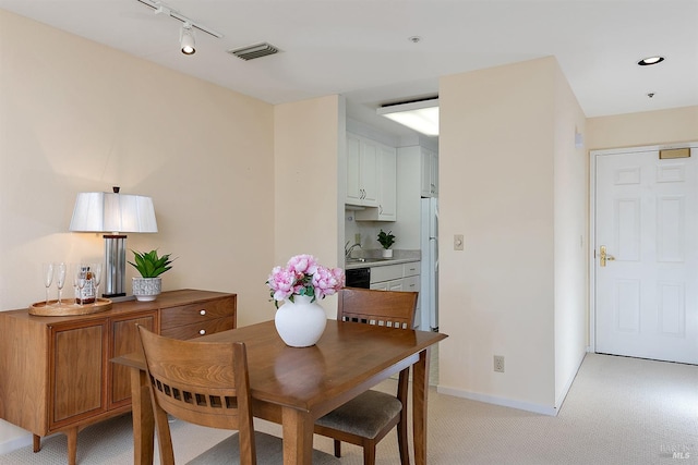 dining area with light carpet, rail lighting, and sink