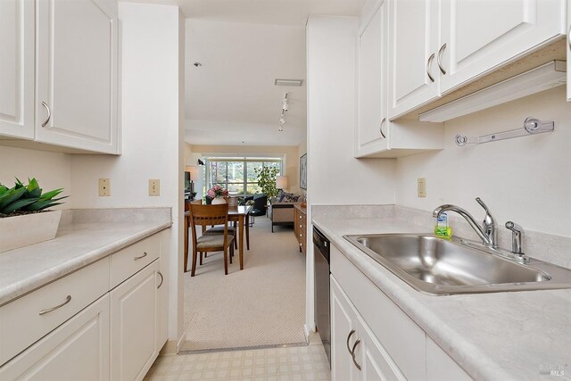 kitchen with stainless steel dishwasher, sink, white cabinetry, and light colored carpet