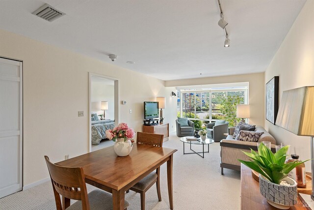 dining area featuring light colored carpet and rail lighting