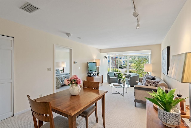 dining room featuring light carpet and track lighting