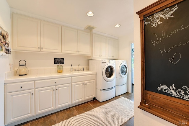 laundry area with cabinets, independent washer and dryer, sink, and dark tile patterned floors