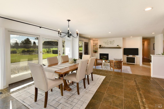 dining space with built in shelves, dark tile patterned floors, and a notable chandelier