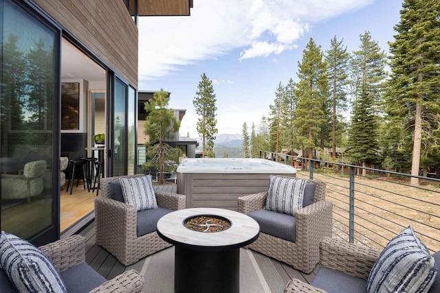 balcony with an outdoor fire pit, a hot tub, and a mountain view