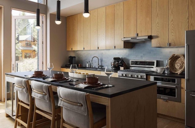 kitchen with sink, appliances with stainless steel finishes, hanging light fixtures, tasteful backsplash, and light brown cabinets