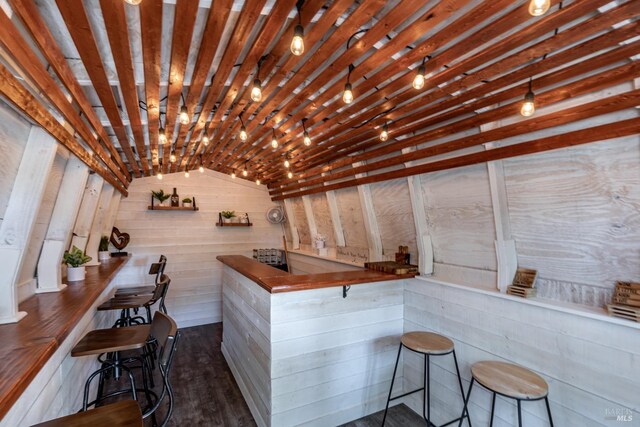 bar with dark hardwood / wood-style flooring, lofted ceiling, and brick ceiling