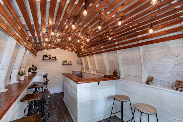bar featuring lofted ceiling, dark wood finished floors, and wooden walls