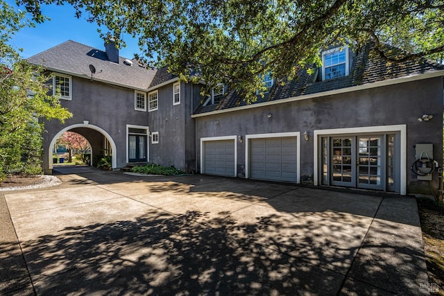view of front facade with a garage, driveway, and stucco siding