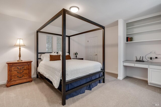 carpeted bedroom featuring built in desk