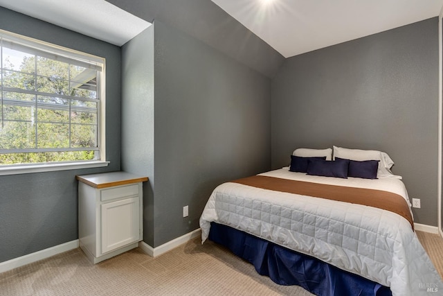 bedroom with a textured wall, baseboards, and light colored carpet