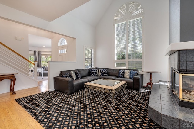 living room with wood-type flooring, a high ceiling, and a tiled fireplace