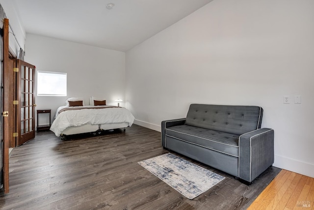 bedroom featuring dark wood-type flooring, lofted ceiling, and baseboards