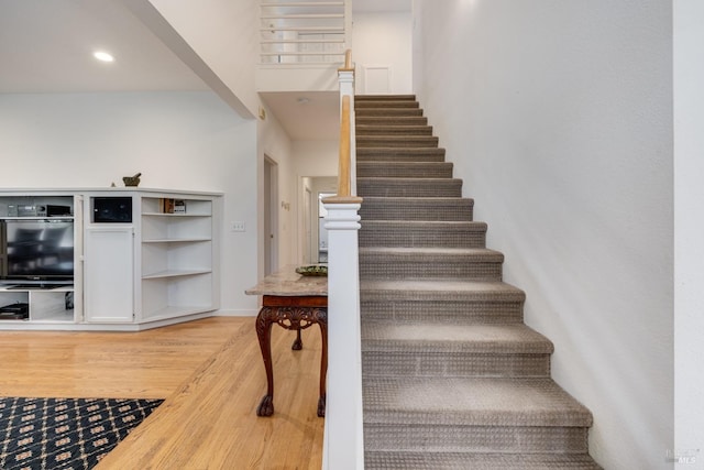 stairway featuring recessed lighting, wood finished floors, and baseboards