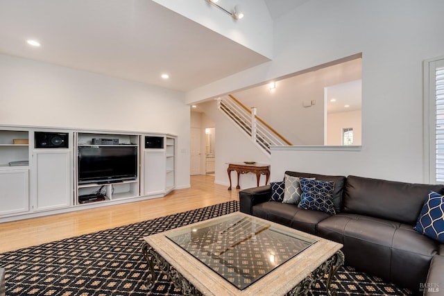 living room featuring light wood-style flooring, recessed lighting, and stairway