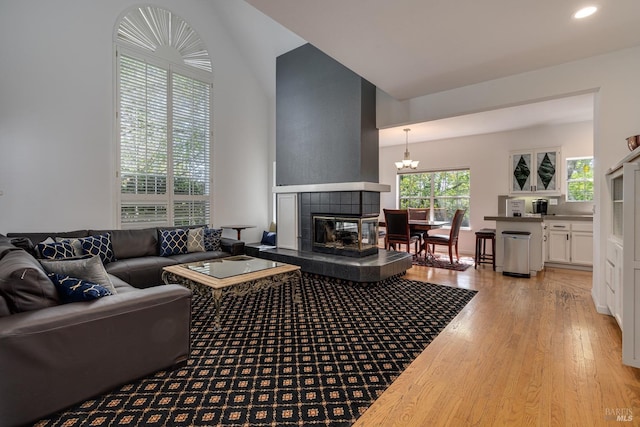 living room with an inviting chandelier, a tile fireplace, and light hardwood / wood-style flooring