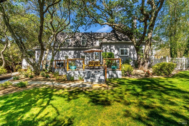 rear view of house featuring a wooden deck and a yard