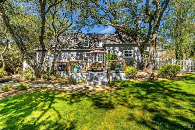 rear view of property featuring a yard, fence, and a deck