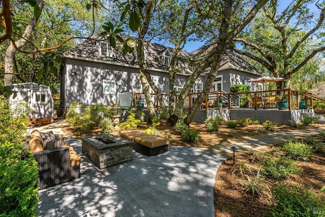 exterior space with a storage shed, a patio area, an outdoor living space with a fire pit, and an outdoor structure