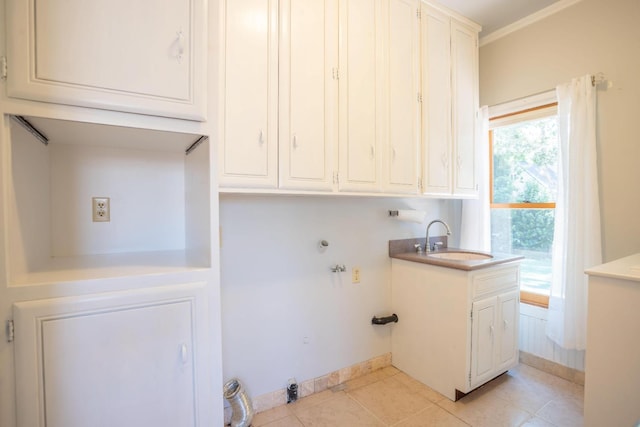 laundry area with cabinet space, light tile patterned flooring, a sink, hookup for a washing machine, and baseboards