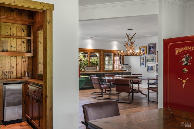 dining room with a chandelier, crown molding, and light wood-type flooring