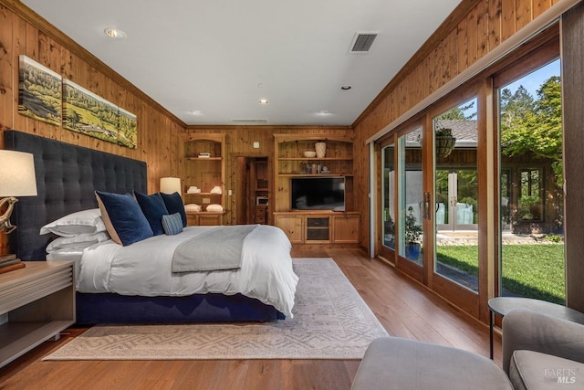 bedroom featuring light hardwood / wood-style flooring, access to outside, and wooden walls