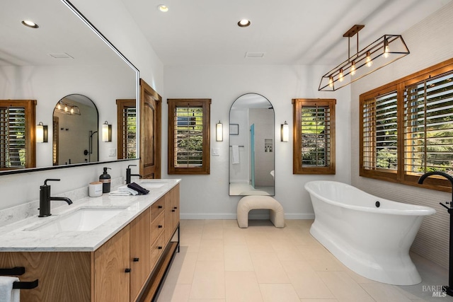 bathroom featuring tile patterned floors, a tub to relax in, a wealth of natural light, and dual bowl vanity