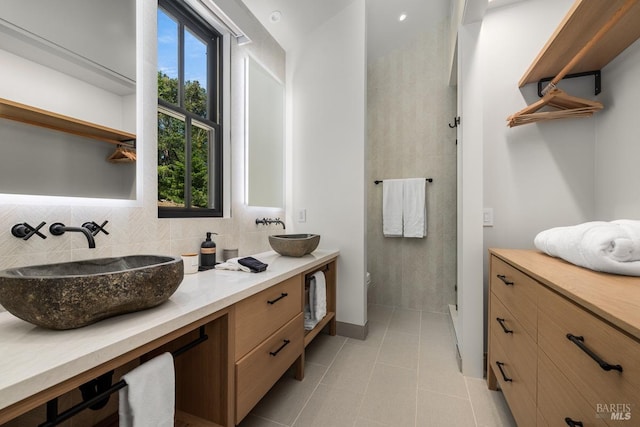 bathroom featuring tile patterned floors, plenty of natural light, backsplash, and double vanity