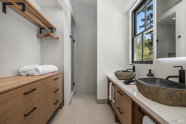 bathroom with a shower with shower door, tile patterned floors, dual vanity, and tile walls