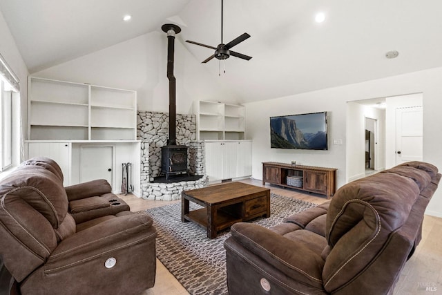 living room featuring ceiling fan, light hardwood / wood-style floors, a wood stove, and vaulted ceiling