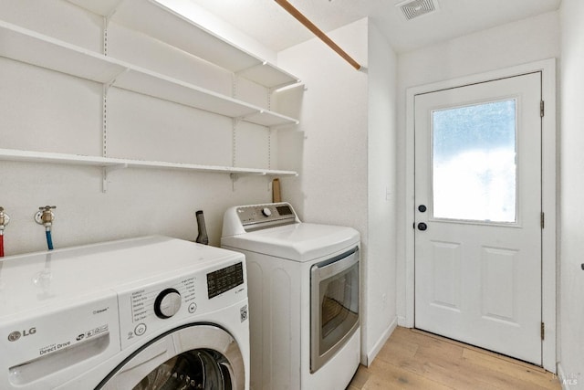 clothes washing area with washing machine and dryer and light hardwood / wood-style floors