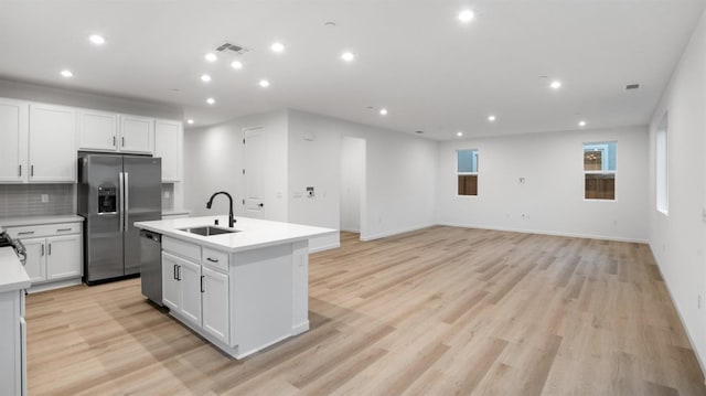 kitchen featuring an island with sink, stainless steel appliances, light hardwood / wood-style flooring, sink, and white cabinets