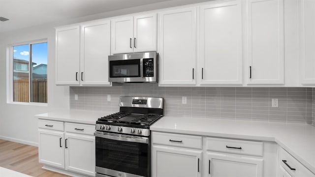 kitchen featuring backsplash, white cabinets, stainless steel appliances, and light hardwood / wood-style floors