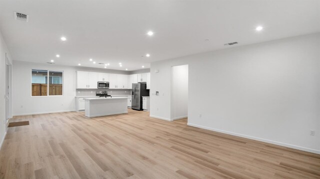 kitchen featuring light wood-type flooring, white cabinetry, stainless steel appliances, and a kitchen island