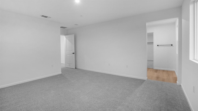 unfurnished bedroom with light colored carpet and a walk in closet